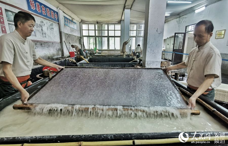 周东红和手工艺人进行”捞纸“。整个过程虽然不过几秒，但是宣纸的质量就全在这一“捞”上。周坤 摄