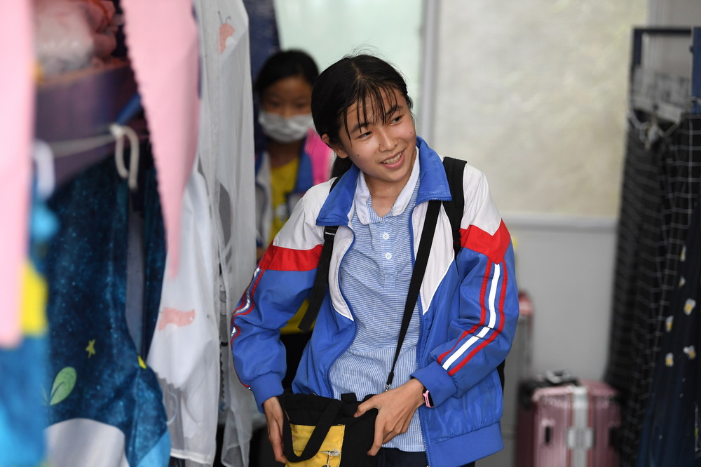 6月19日，在金寨县三合实验学校宿舍，蔡齐艳放学后收拾行李准备回家过周末 。
